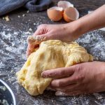 person holding bread on brown wooden table